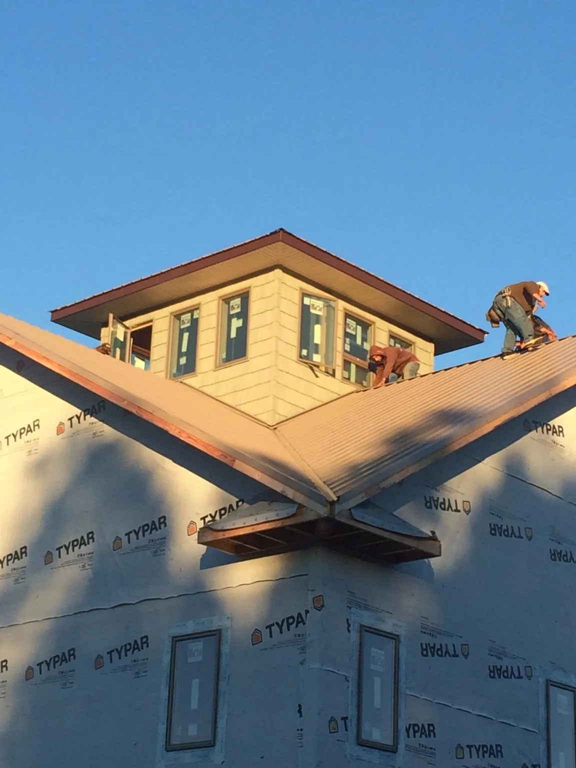 Roofers working around a rooftop cupola on a new metal roof at sunset — Roof Waterproofing in Moscow by Roofing Brothers